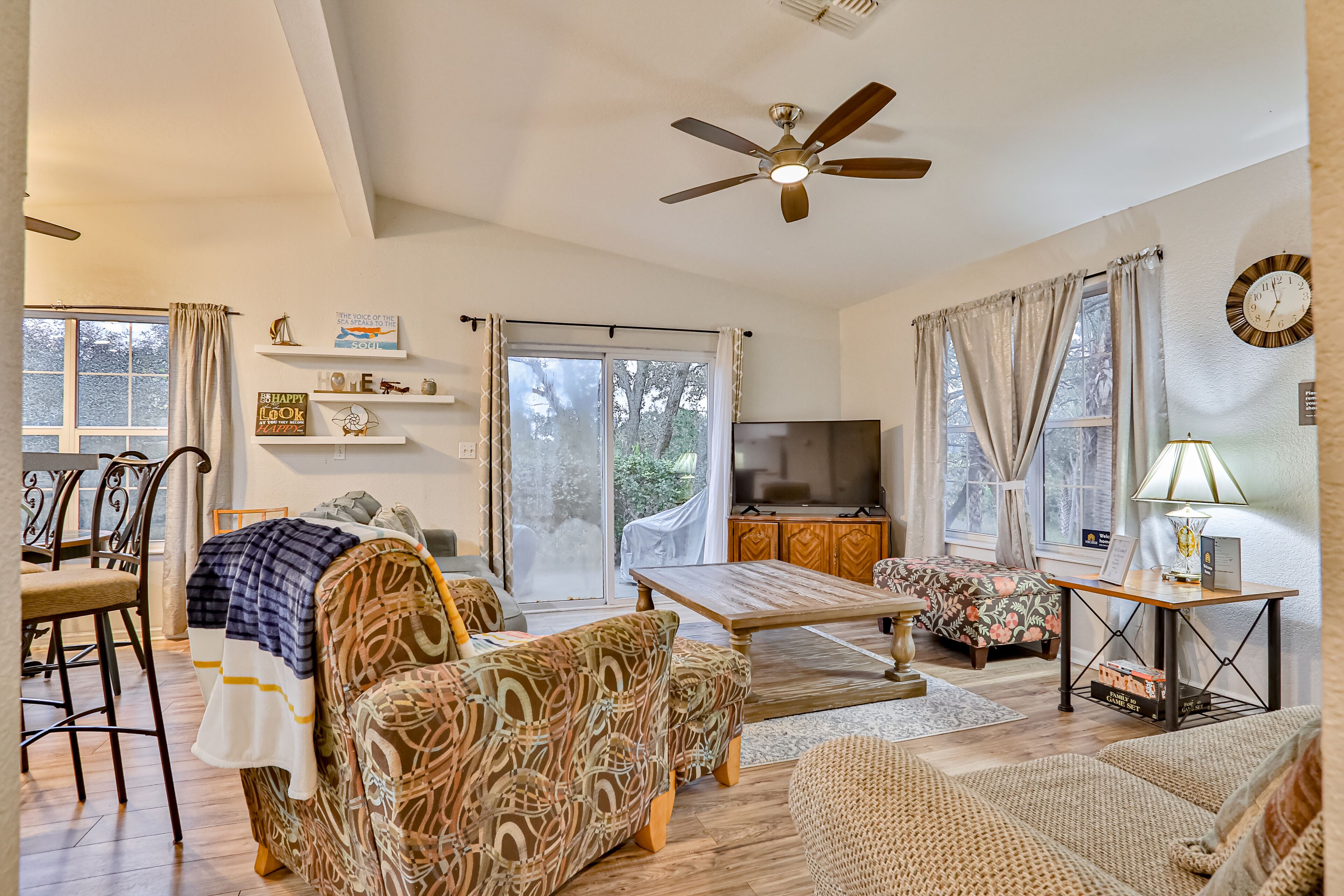 A spacious living room with a sofa, armchair, dining table, and a television.
