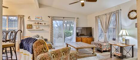 A spacious living room with a sofa, armchair, dining table, and a television.