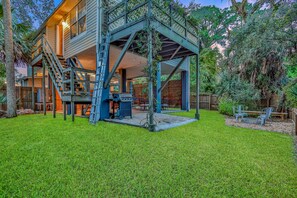 Una casa con un porche cubierto, una escalera que lleva al piso superior y un césped bien cuidado.