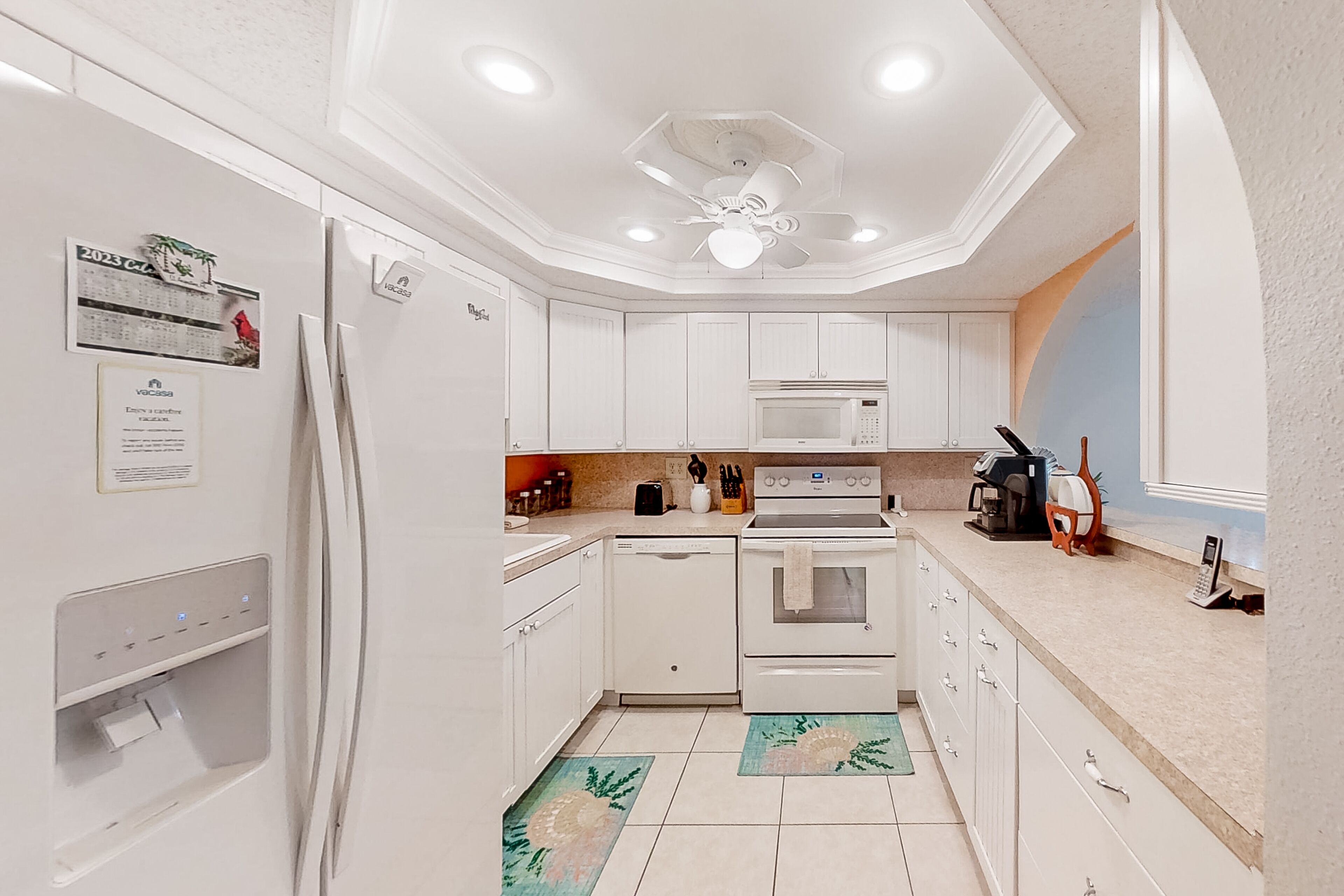 A modern kitchen with white cabinets, a built-in microwave, a stove, and a water dispenser.