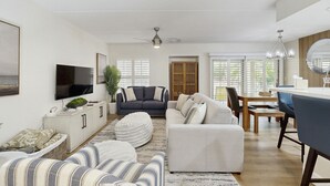 Ein modernes Wohnzimmer mit einer Couch, einem Hocker und einem Flachbildfernseher.
