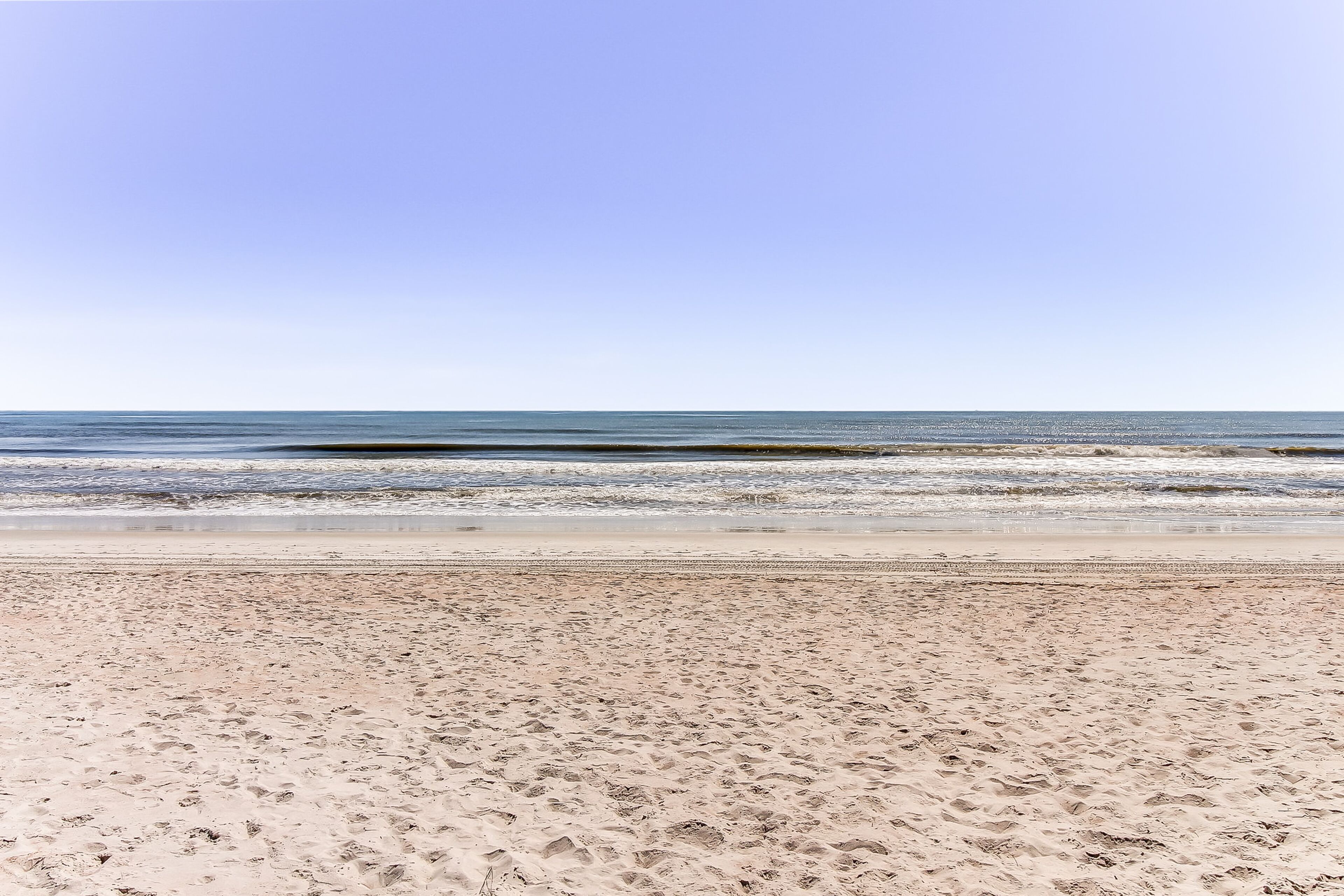 A beach with a clear sky and calm sea.