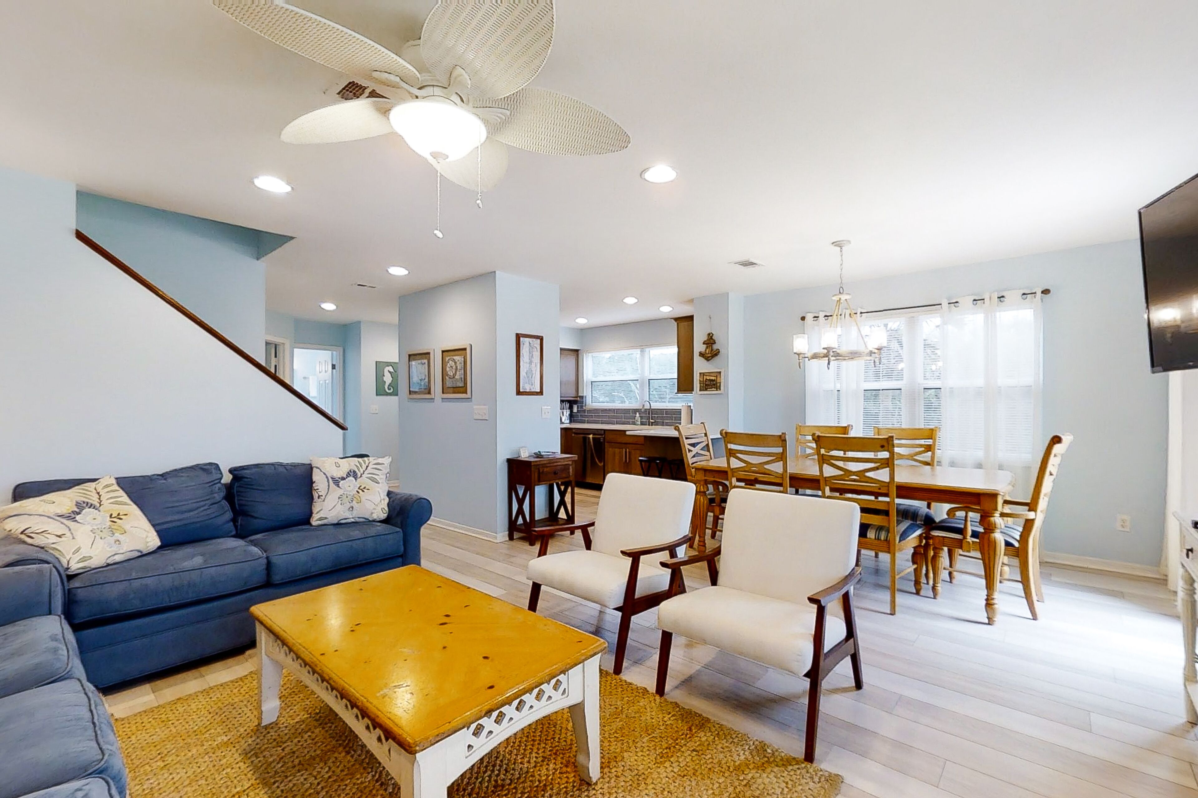 A living room with a sofa, coffee table, and dining area with chairs and a table.