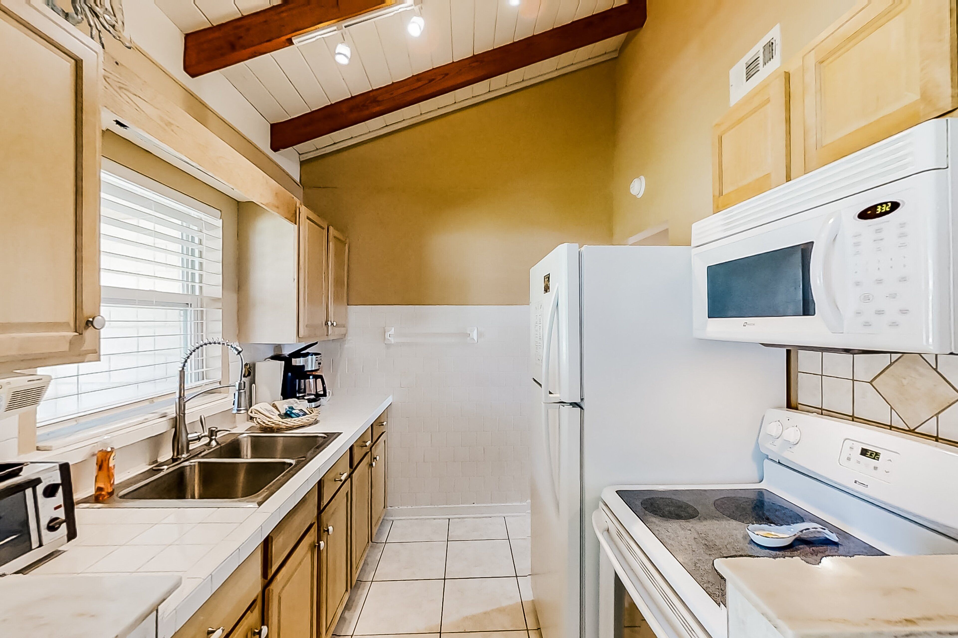 A compact kitchen with white appliances, a sink, and wooden cabinets.