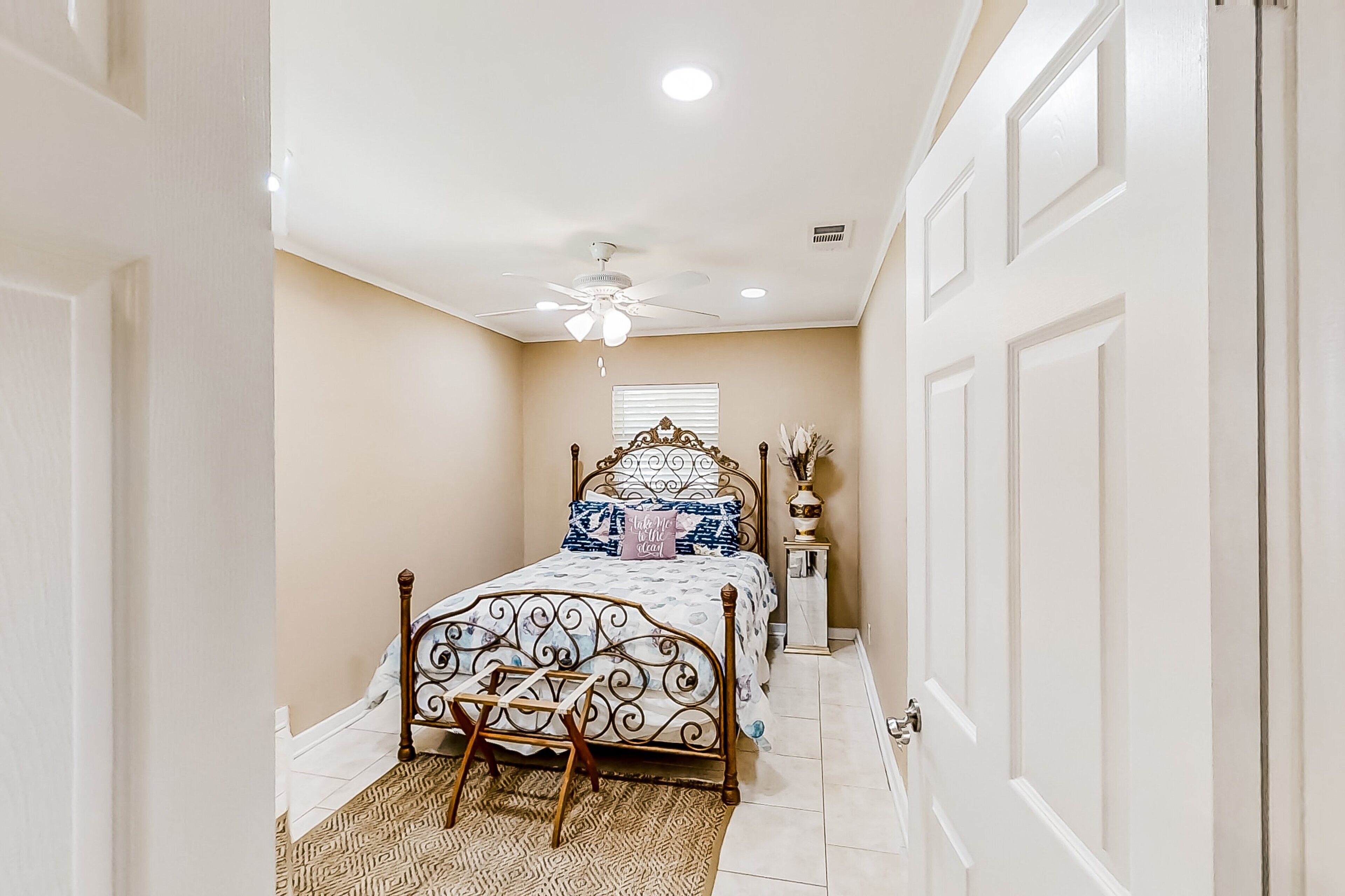 A bedroom with a bed, a ceiling fan, a bedside table, and a window.