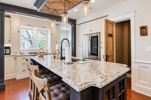 A kitchen with a large island, white cabinetry, and a wooden ceiling. - Extraordinary Old Florida Home With Designer Interior & Backyard Treehouse (St. Augustine)