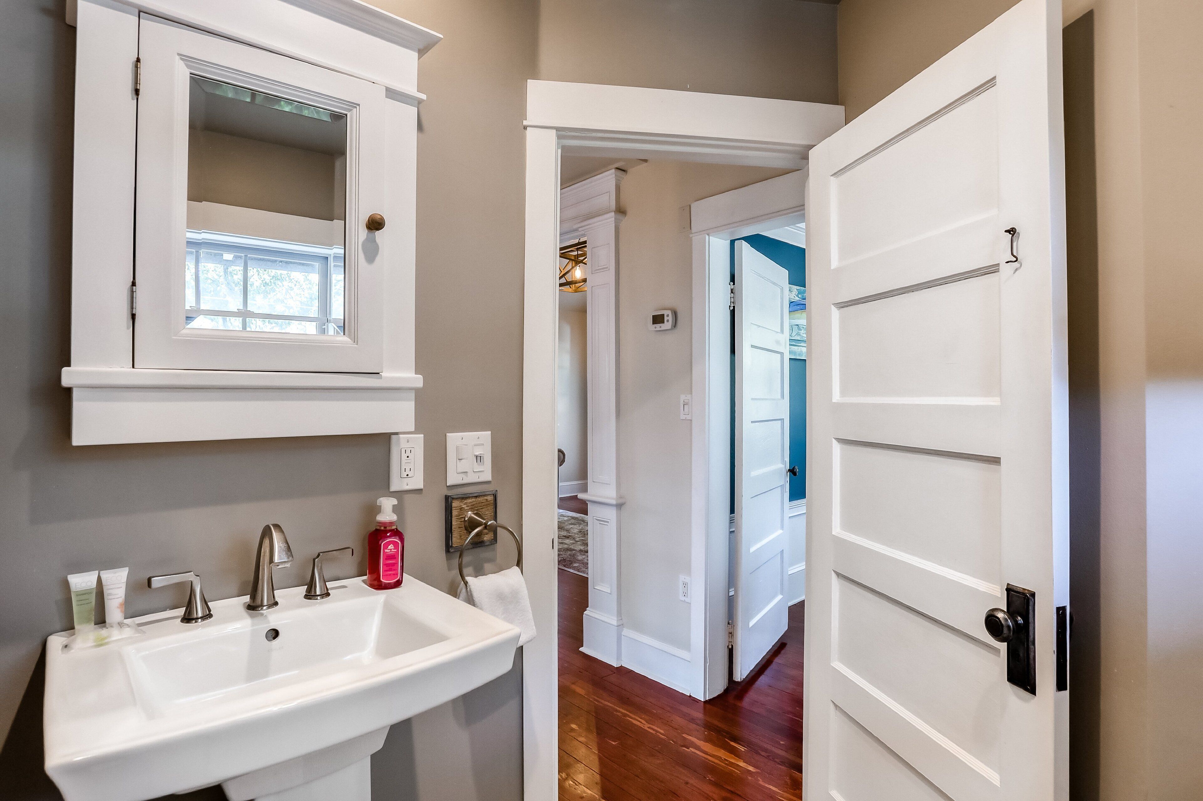 Une salle de bain avec un lavabo blanc, un miroir et un porte-serviettes.
