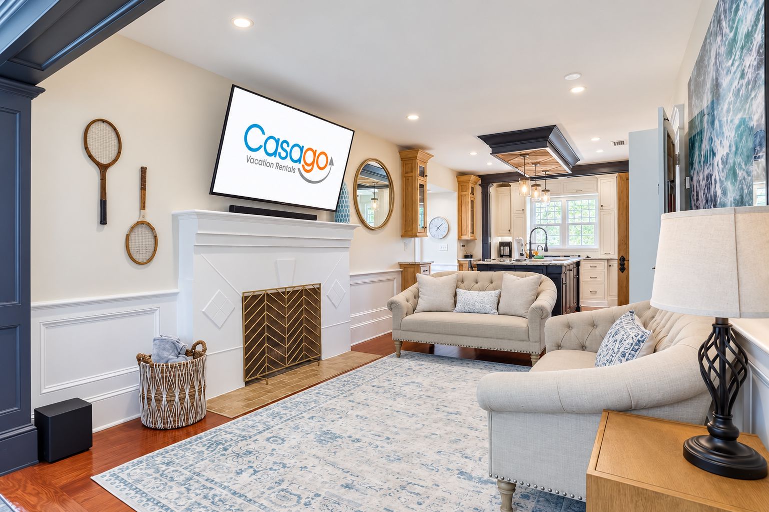 Sala de estar com lareira, televisão exibindo 'Casago Vacation Rentals' e cozinha ao fundo.