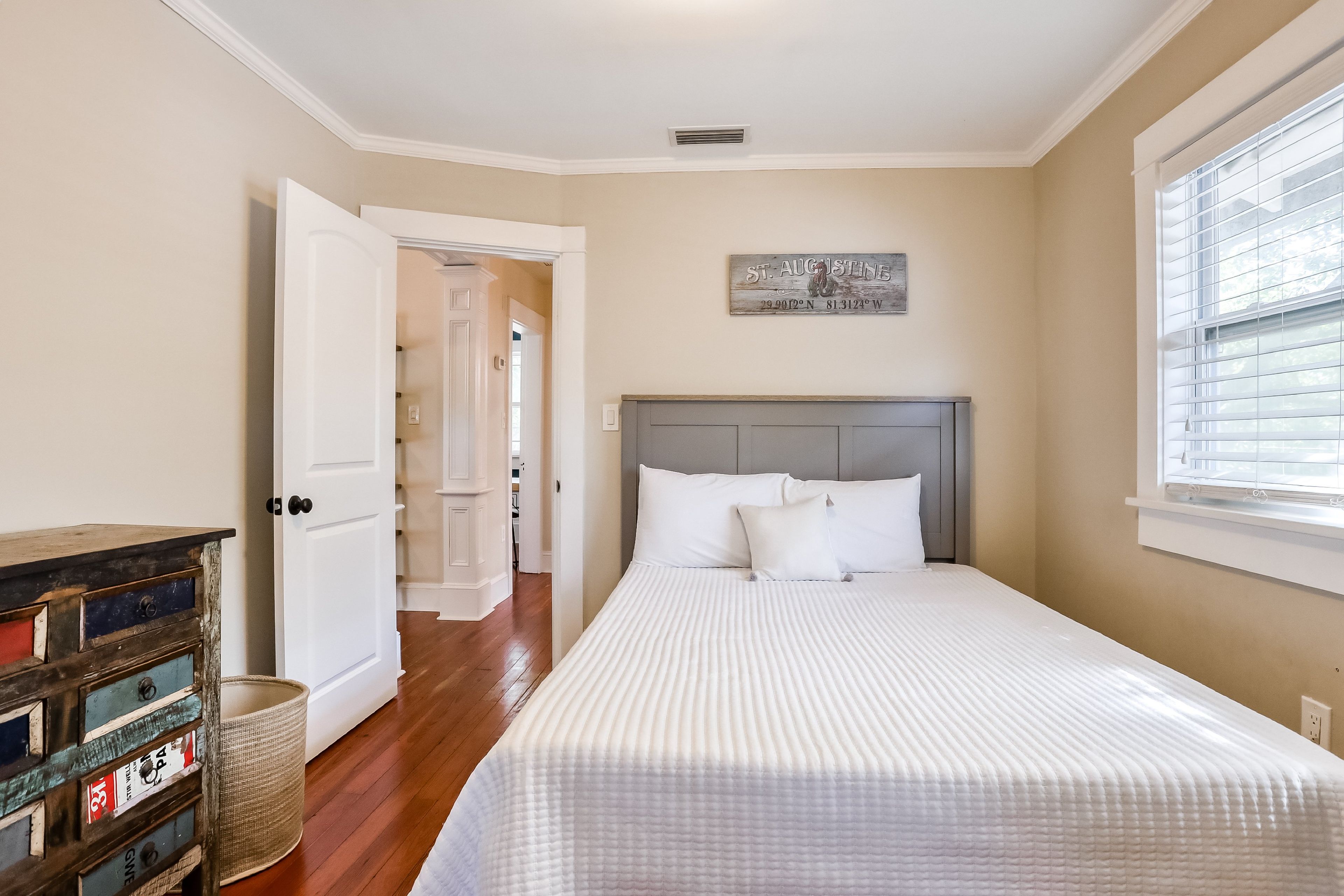 Een slaapkamer met een bed, een lakenkast en een deur naar een andere kamer.