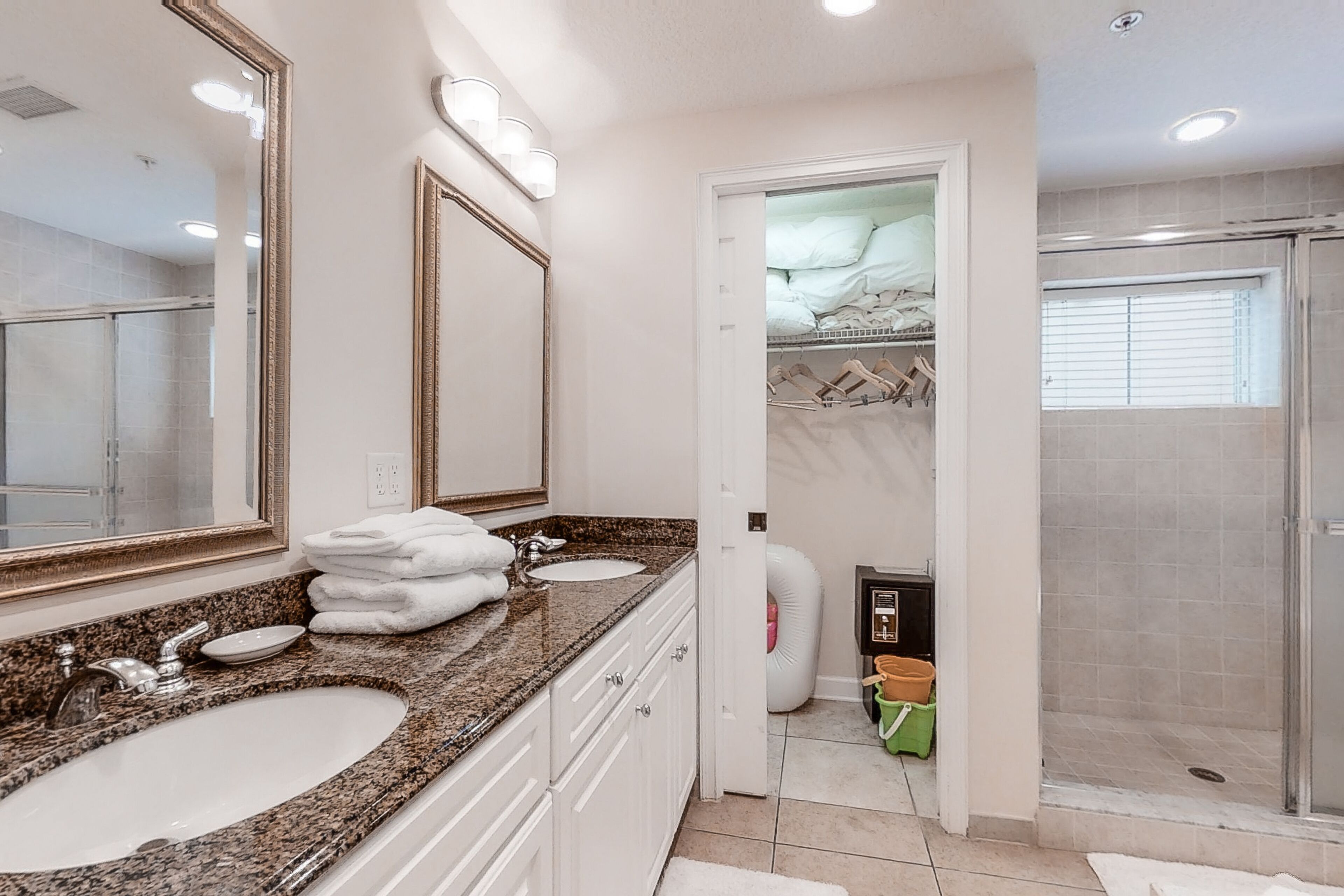 A bathroom with two sinks, a large mirror, and a walk-in shower.
