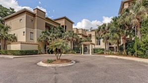 A multi-story hotel with a central courtyard, palm trees, and a covered walkway. - Dog-friendly Tennis Villa Suite in Amelia Island W/shared Pool, Free Wifi (Fernandina Beach)