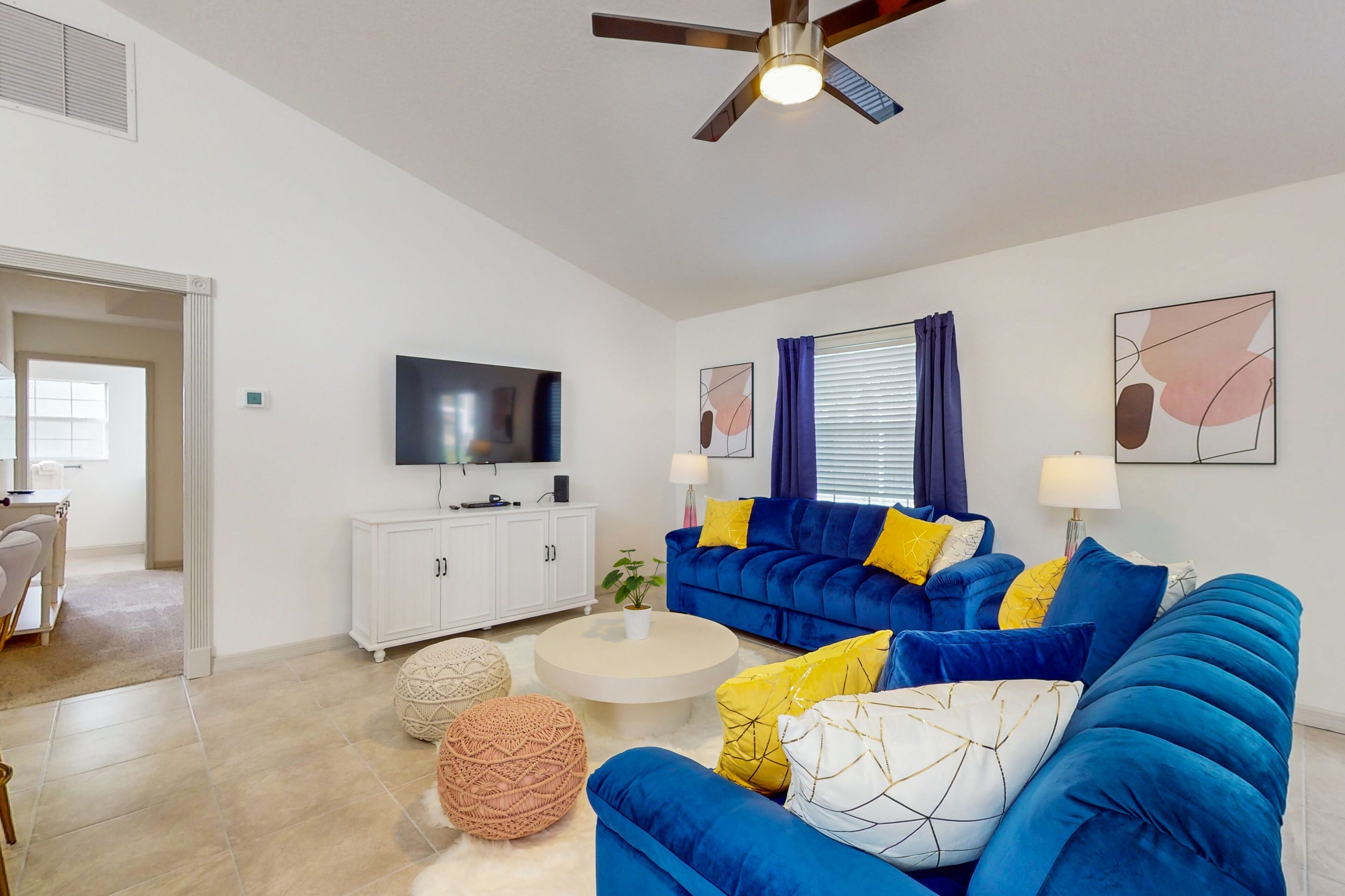 A modern living room with a blue sofa, white coffee table, and a ceiling fan.