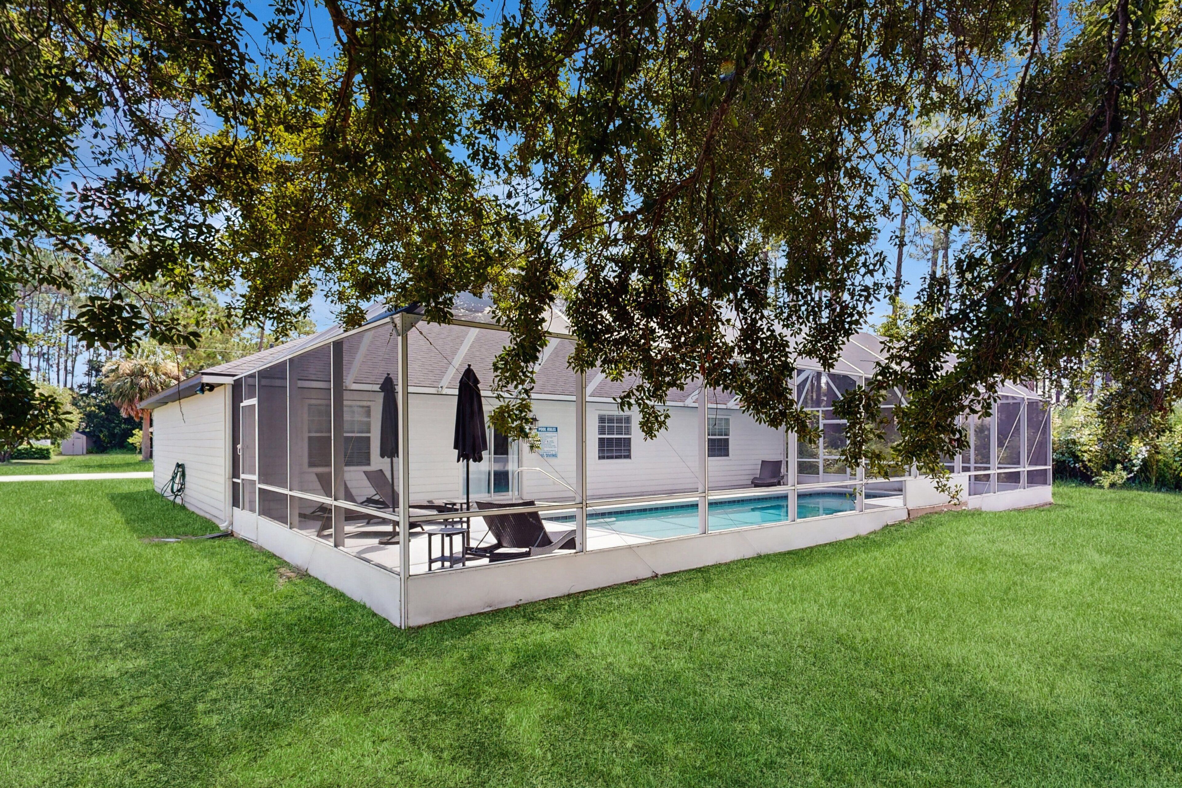 Une maison moderne dotée d’un grand patio entièrement vitré, d’une piscine et d’une pelouse bien entretenue.