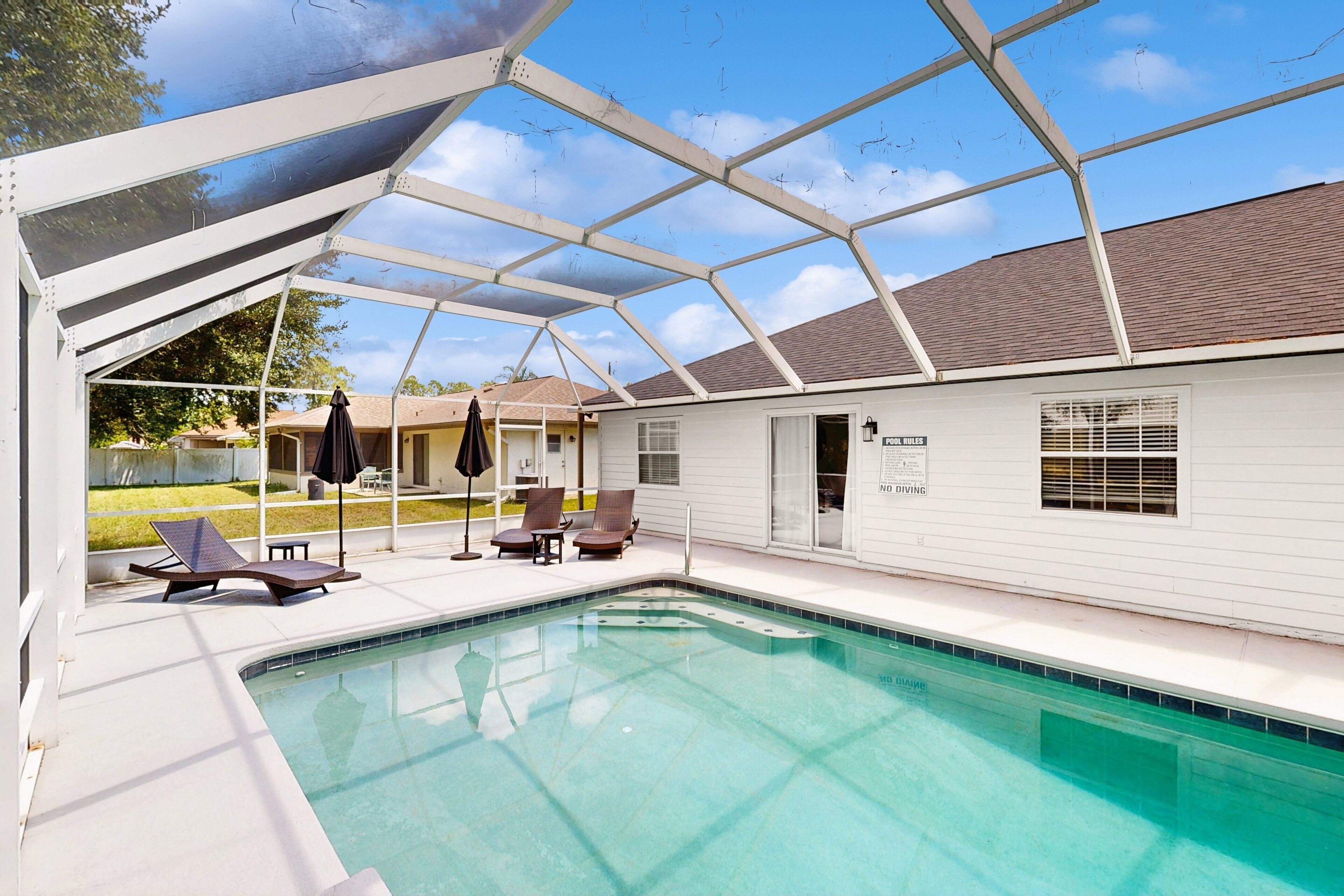 A covered outdoor swimming pool with lounge chairs and a patio area.