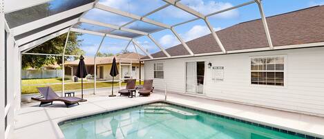 A covered outdoor swimming pool with lounge chairs and a patio area.