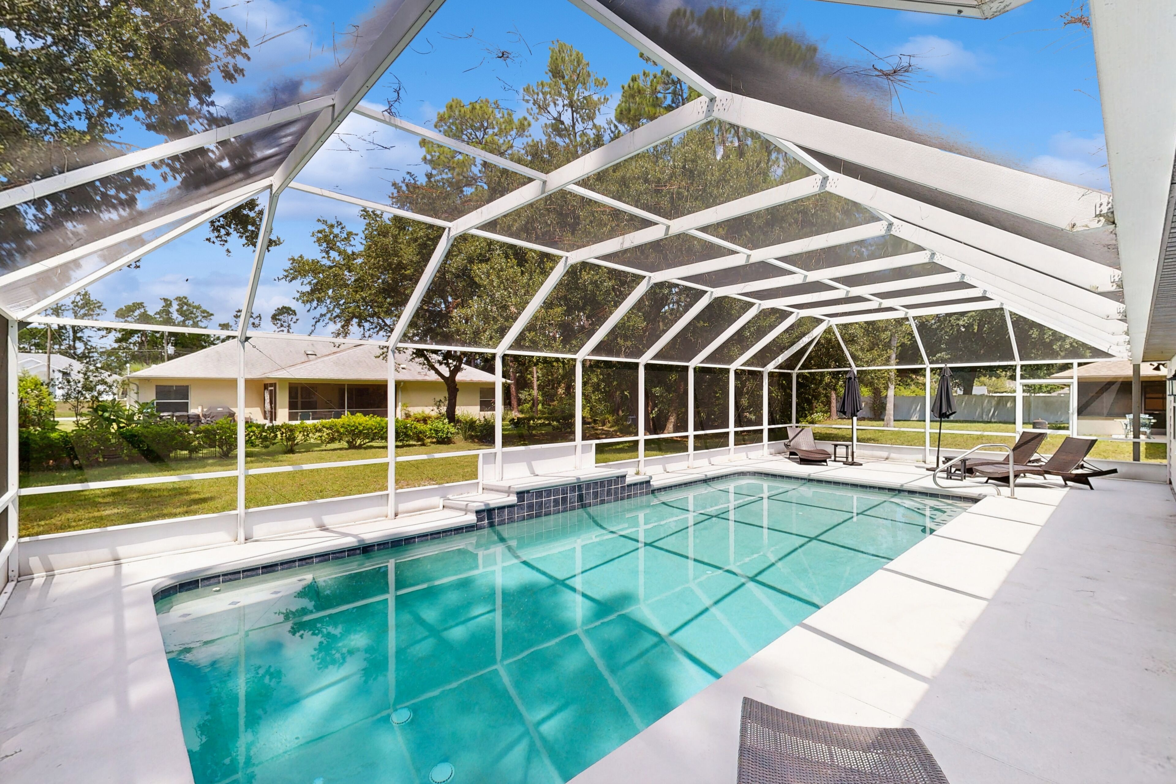 Una piscina techada con una vista despejada del paisaje circundante, que incluye árboles y un edificio al fondo.