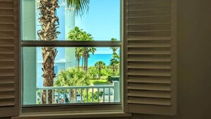 Ein Fenster mit Blick auf einen Balkon, Palmen und einen strahlend blauen Himmel.