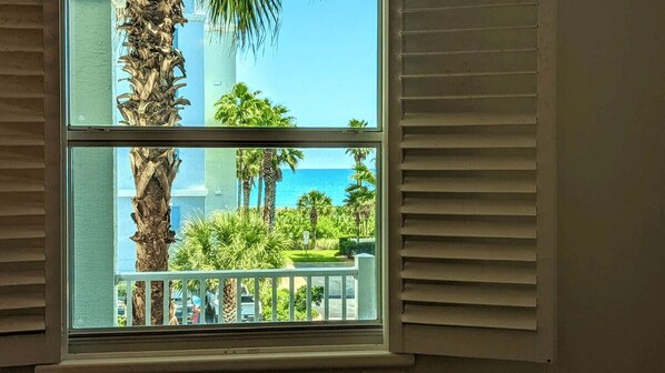 A window with a view of a balcony, palm trees, and a clear blue sky. - Luxurious Beach Villa Steps to Cinnamon Beach! Ocean and Lake Views (Palm Coast)