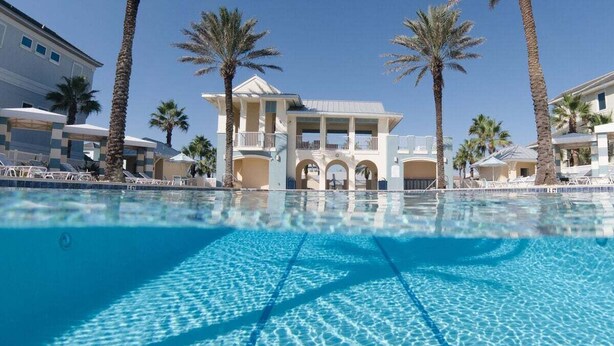 Ein Hotel mit Pool, Palmen und einem Gebäude mit Balkonen.