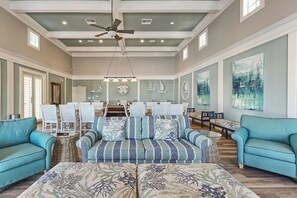 Ein geräumiges Wohnzimmer mit einer großen, gestreiften Couch, zwei Zierteilen, einem Deckenventilator und Kunstwerken an den Wänden.