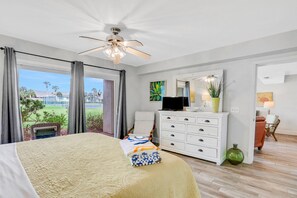 A bedroom with a bed, a ceiling fan, a dresser, a chair, and a view of the outdoors. - Ground-floor Condo Next to the Tennis Courts With 2 Pools, Sauna, Beach Access (St. Augustine)