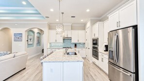 A modern kitchen with white cabinetry, stainless steel appliances, and a marble countertop. - New Custom House! Private, Clean, Safe! Walk to the Beach! (St. Augustine)