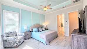 A bedroom with a bed, nightstands, a chair, a ceiling fan, and a television. - New Custom House! Private, Clean, Safe! Walk to the Beach! (St. Augustine)
