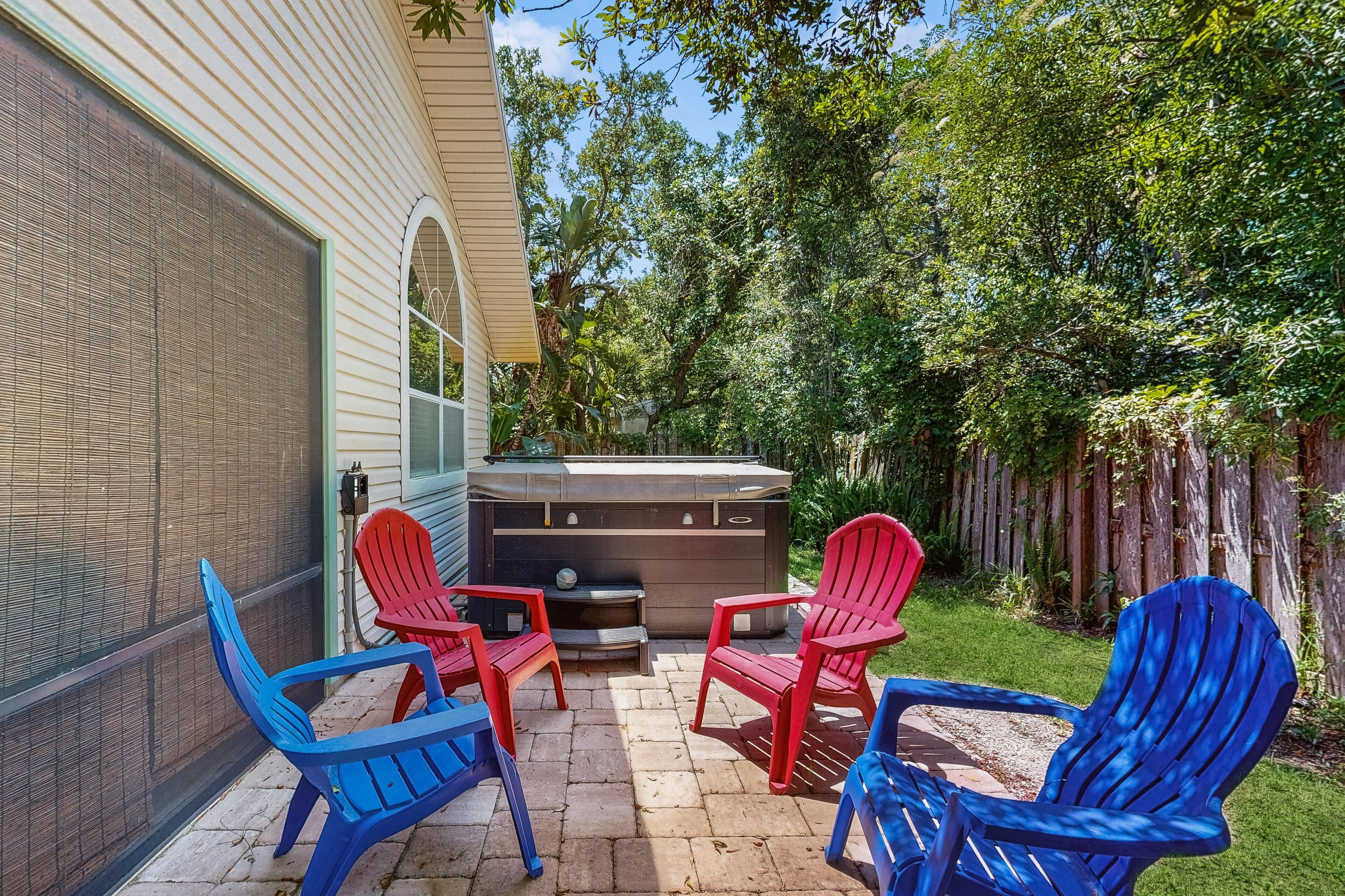 A patio with four Adirondack chairs, a hot tub, and a brick wall.