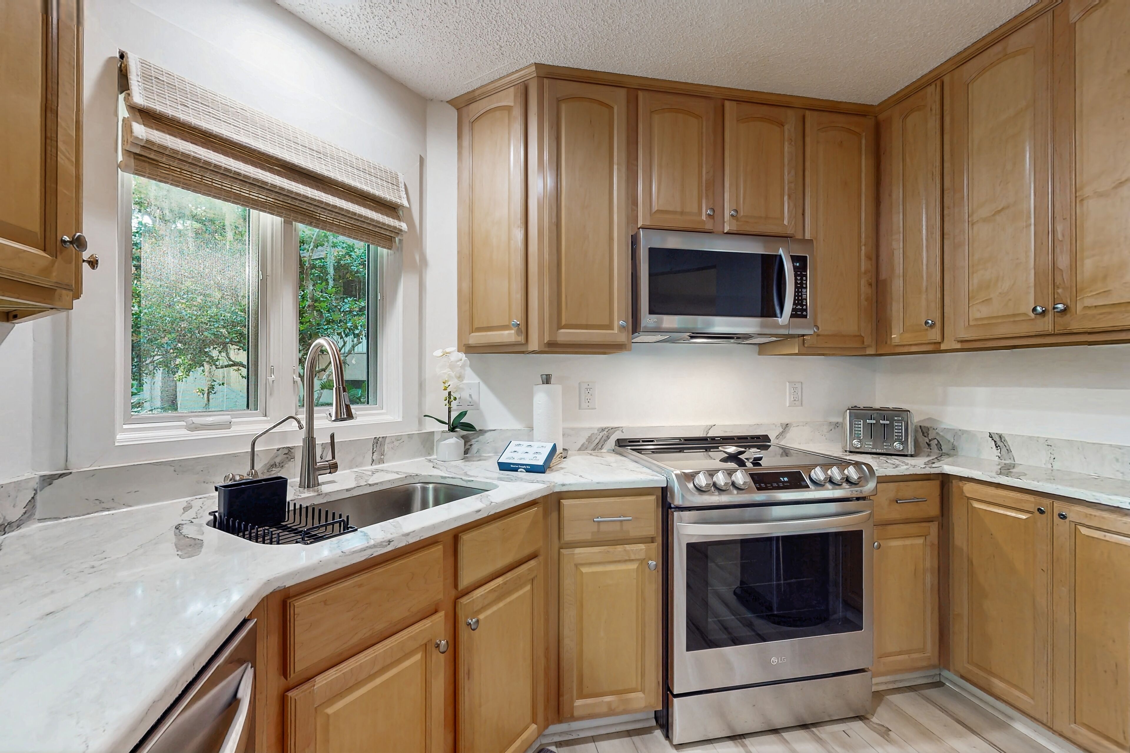 A kitchen with wooden cabinets, a stainless steel microwave, a gas stove, and a sink.