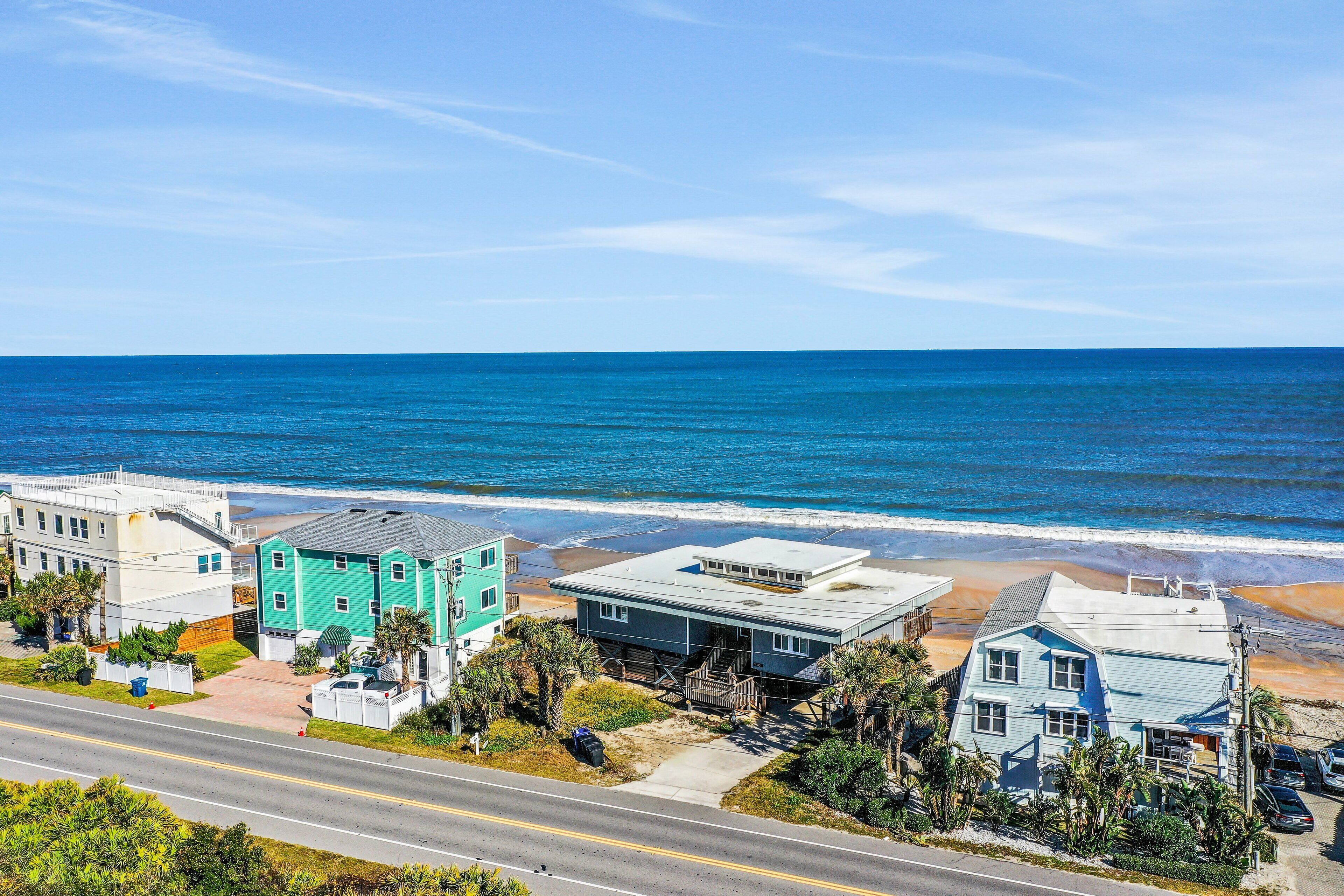 Zona residencial costera con casas cerca de la playa, una carretera y el océano.