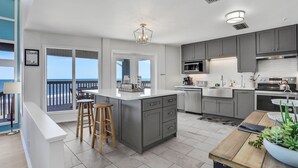 A modern kitchen with grey cabinets, a white island, and a view to the outside. - Gorgeous Beachfront Home With Inviting Deck & Patio, Hammock, Amazing Views (St. Augustine)