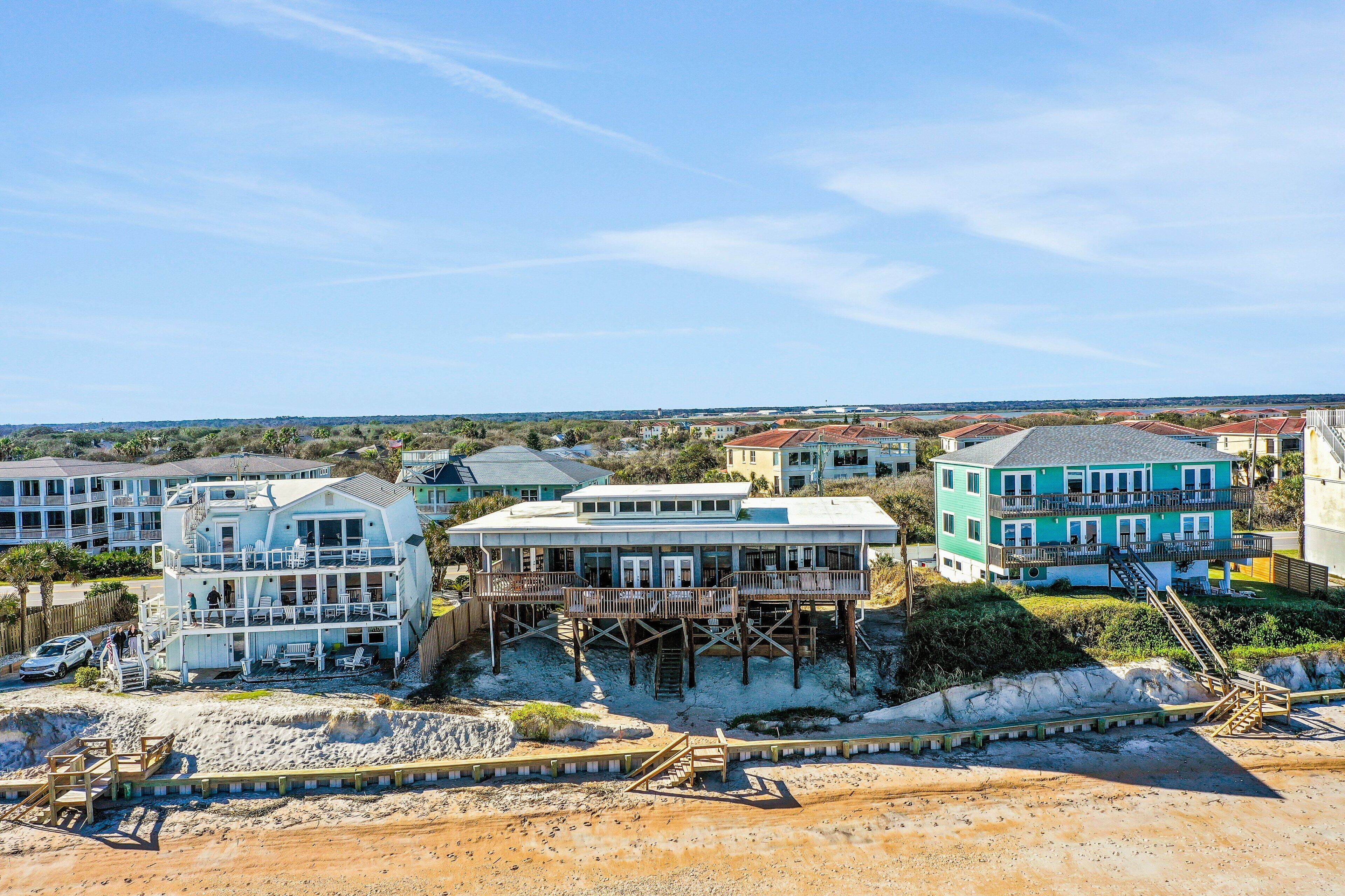 A coastal hotel with multiple buildings, including a large structure with a balcony and a smaller building with a staircase.