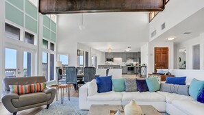 A spacious living room with a large sectional sofa, a coffee table with decorative items, and a dining area with chairs and a table. - Gorgeous Beachfront Home With Inviting Deck & Patio, Hammock, Amazing Views (St. Augustine)