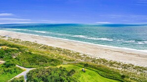 Eine Küstenlandschaft mit Strand, Golfplatz und blauem Himmel.