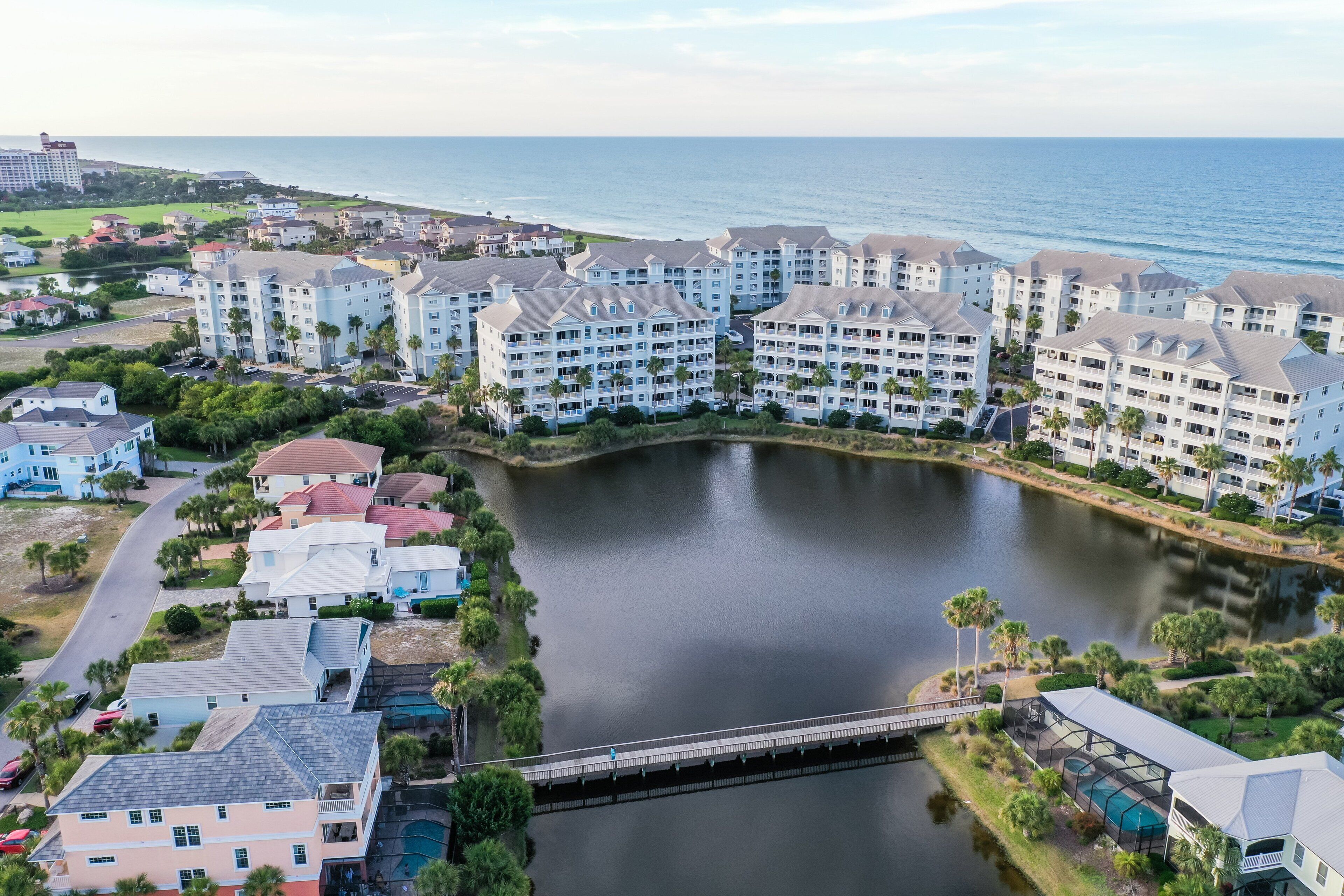 A coastal residential area with multiple multi-story buildings, a bridge, and a body of water.
