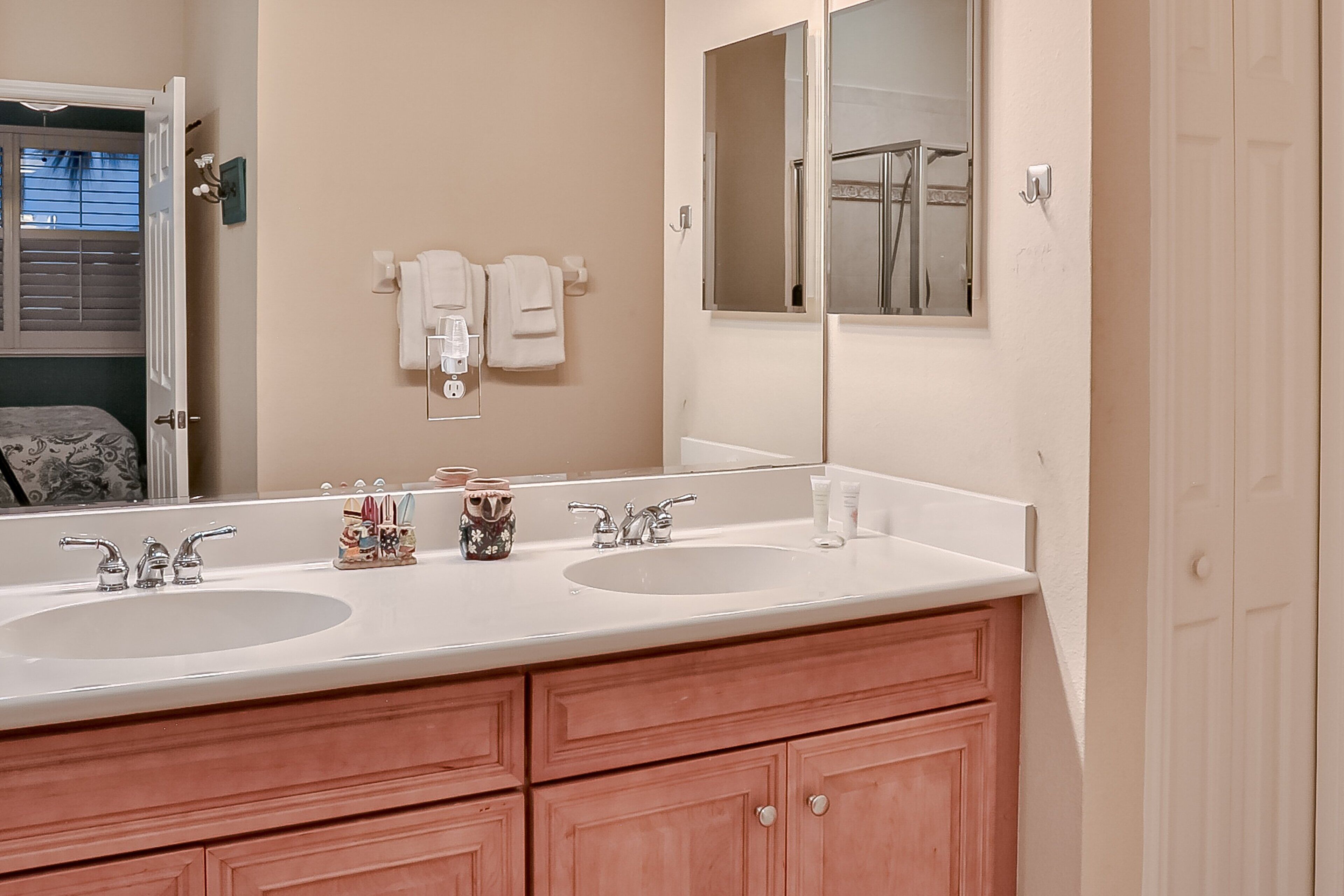 A bathroom with two sinks, a large mirror, and wooden cabinets.
