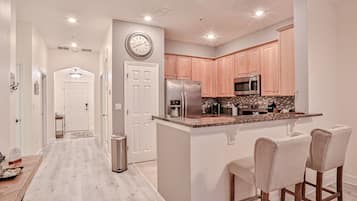 A modern kitchen with wooden cabinets, stainless steel appliances, and a breakfast bar.