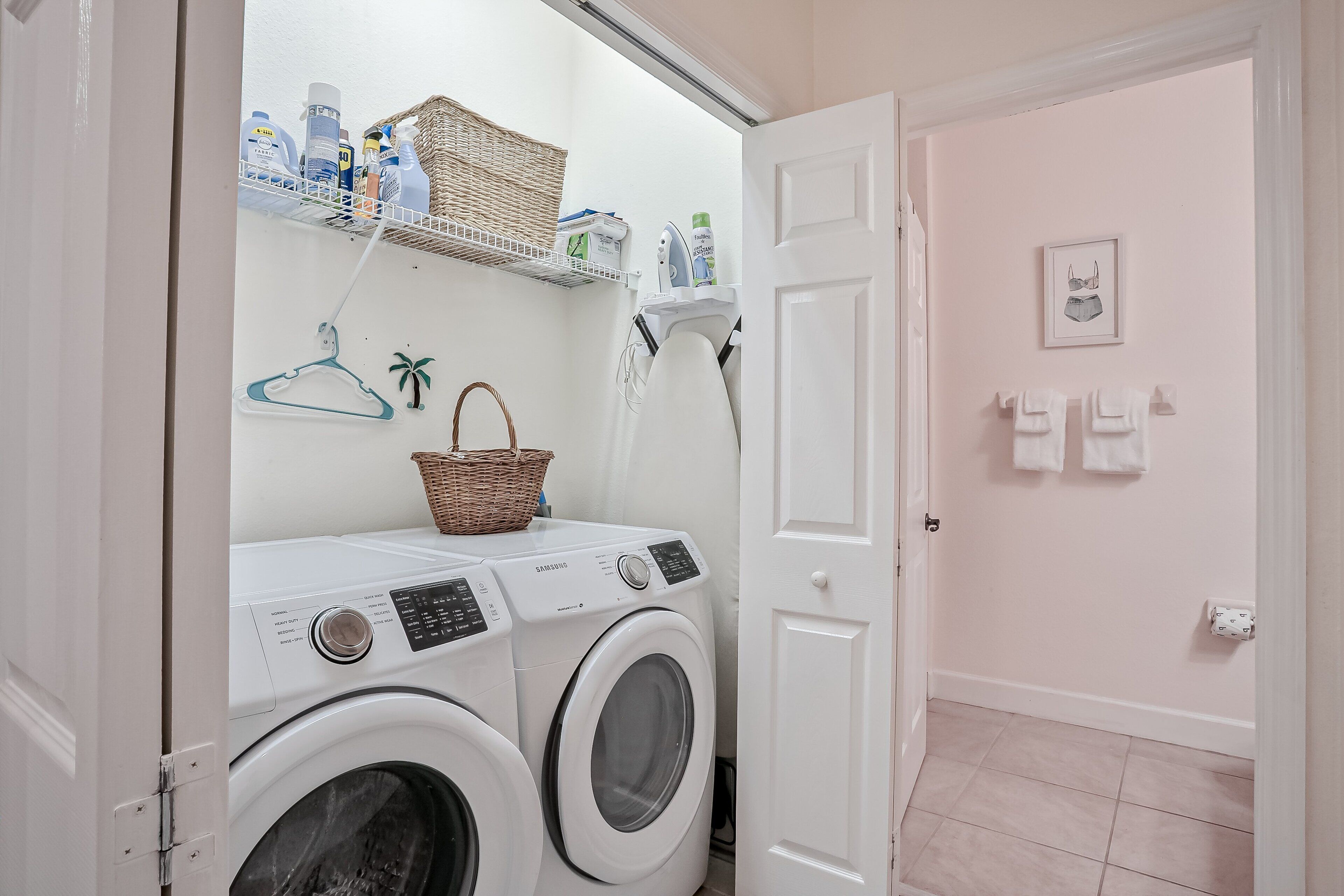 A laundry area with two white washing machines, a basket, and shelves with cleaning supplies.