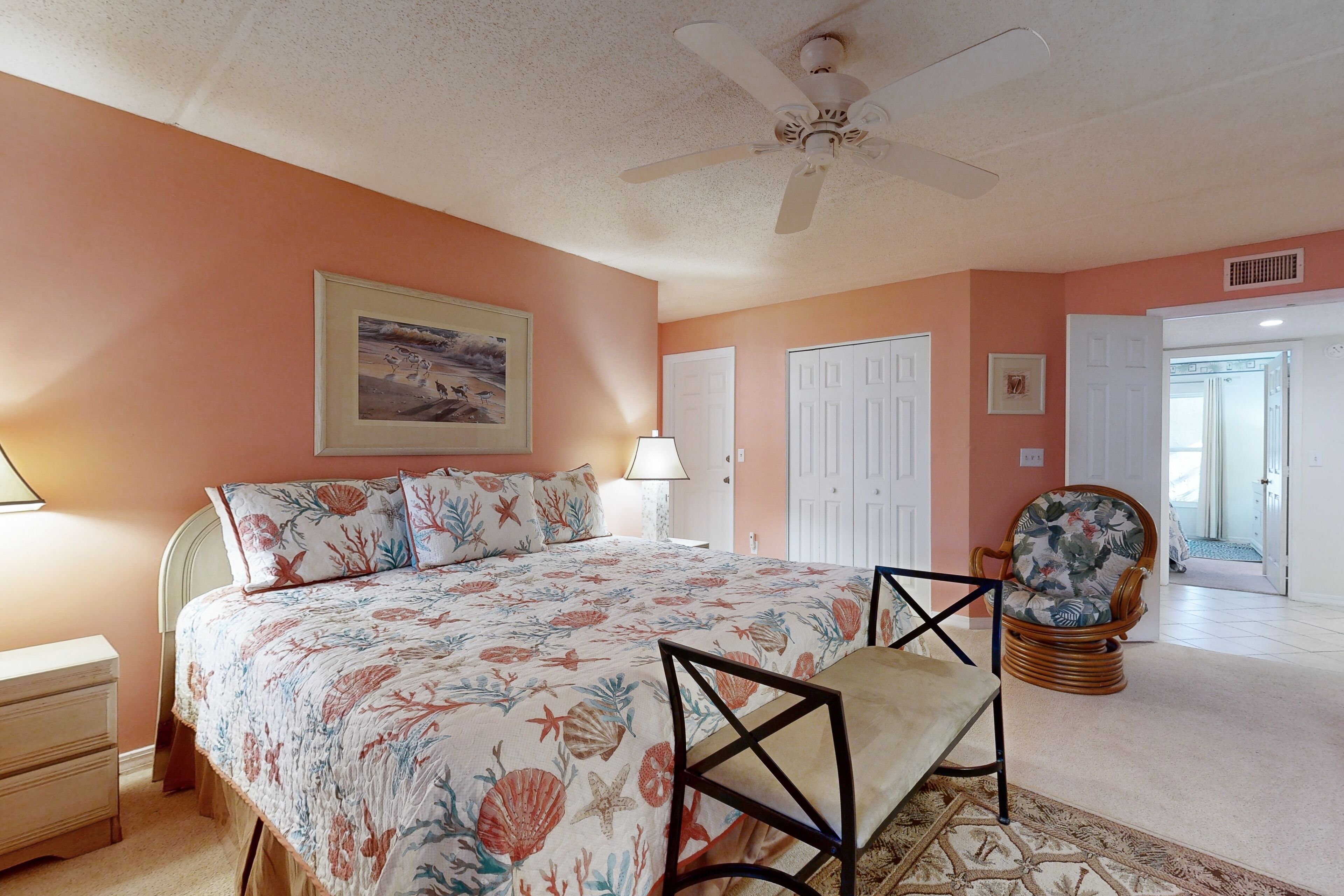 A bedroom with a bed, a chair, a lamp, and a ceiling fan.