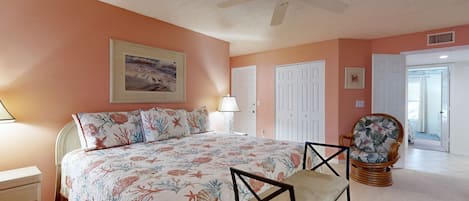 A bedroom with a bed, a chair, a lamp, and a ceiling fan.