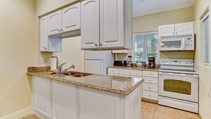 A kitchen with white cabinets, a granite countertop, a built-in oven, and a microwave. - Dog-friendly Home in the Tennis Villas W/free Wifi, Shared Pool, Central AC (Fernandina Beach)