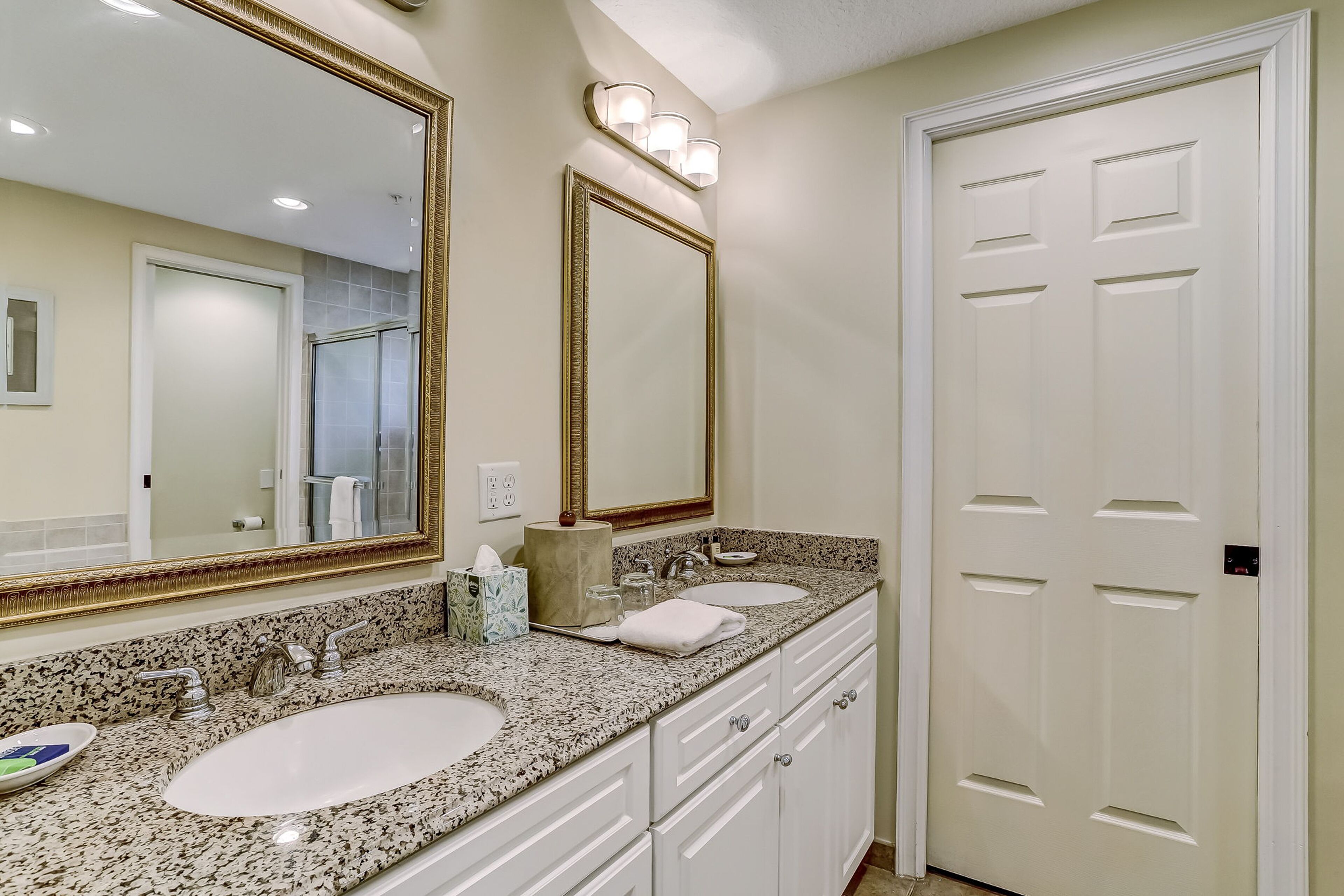 A bathroom with two sinks, a large mirror, and a door.