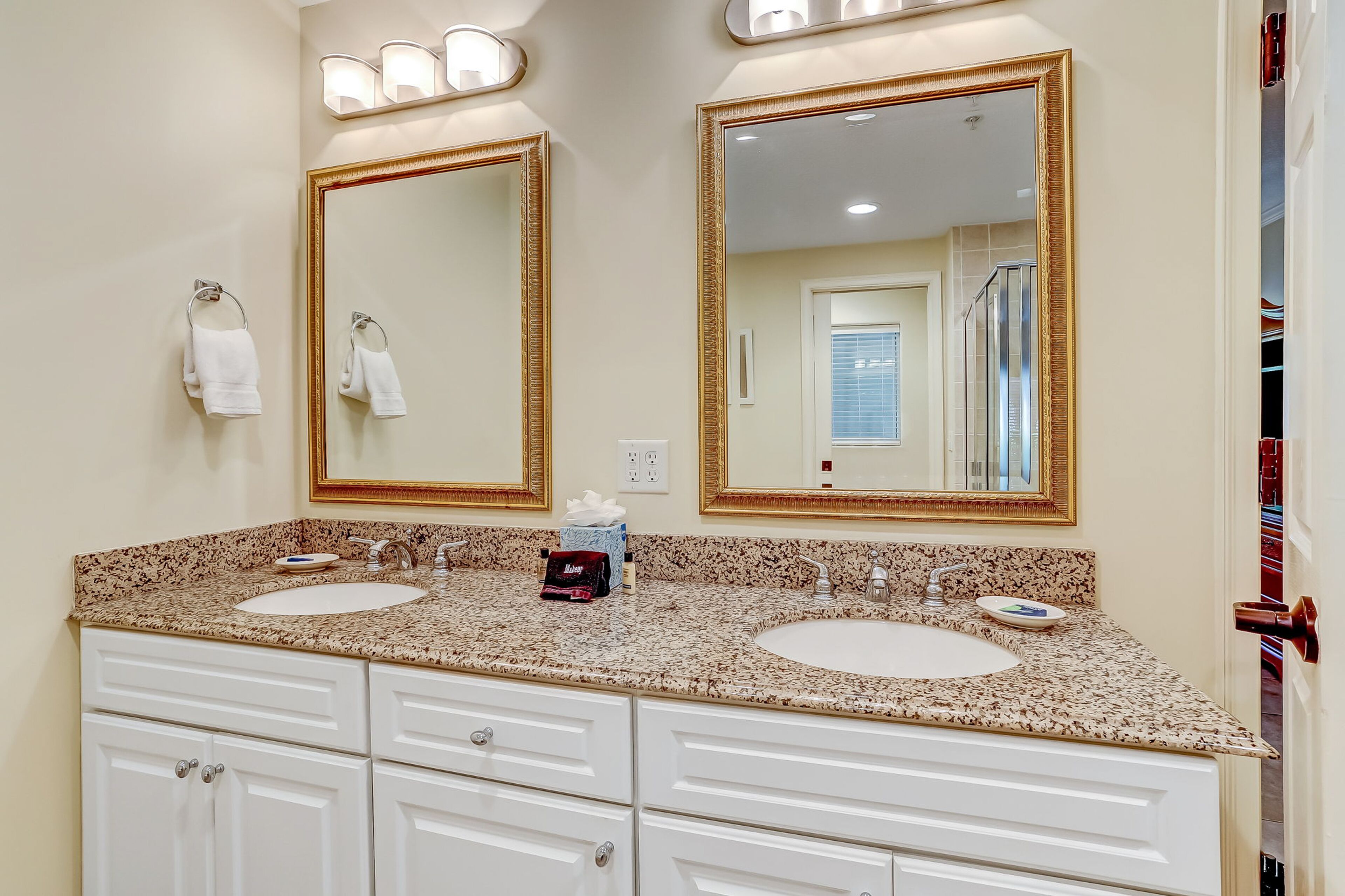 A bathroom with two sinks, a large mirror, and a vanity with drawers.