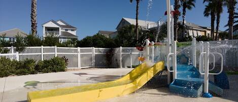A water park with a yellow slide and a water fountain.