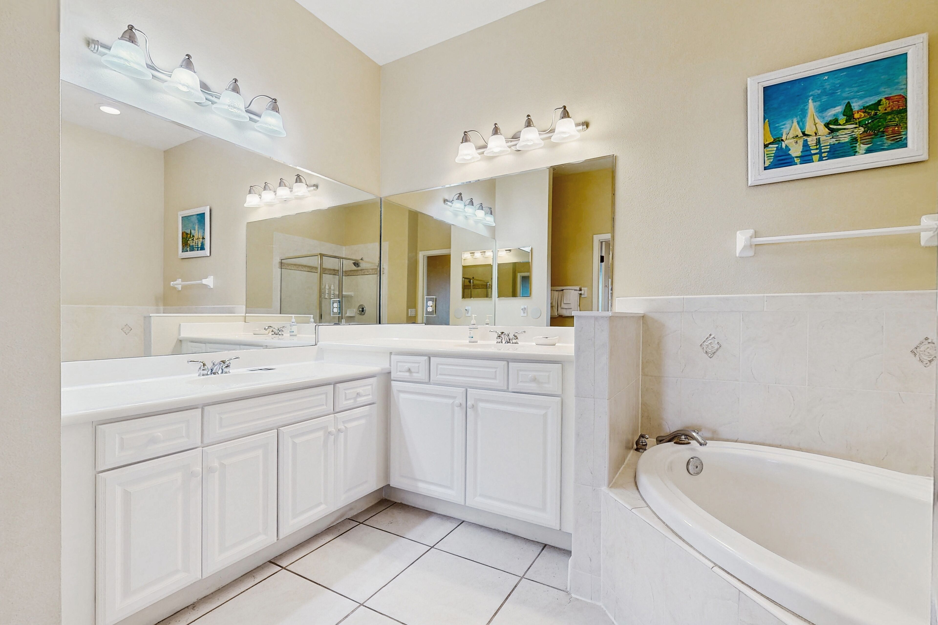 A modern bathroom with a large mirror, dual sinks, a bathtub, and a shower area.