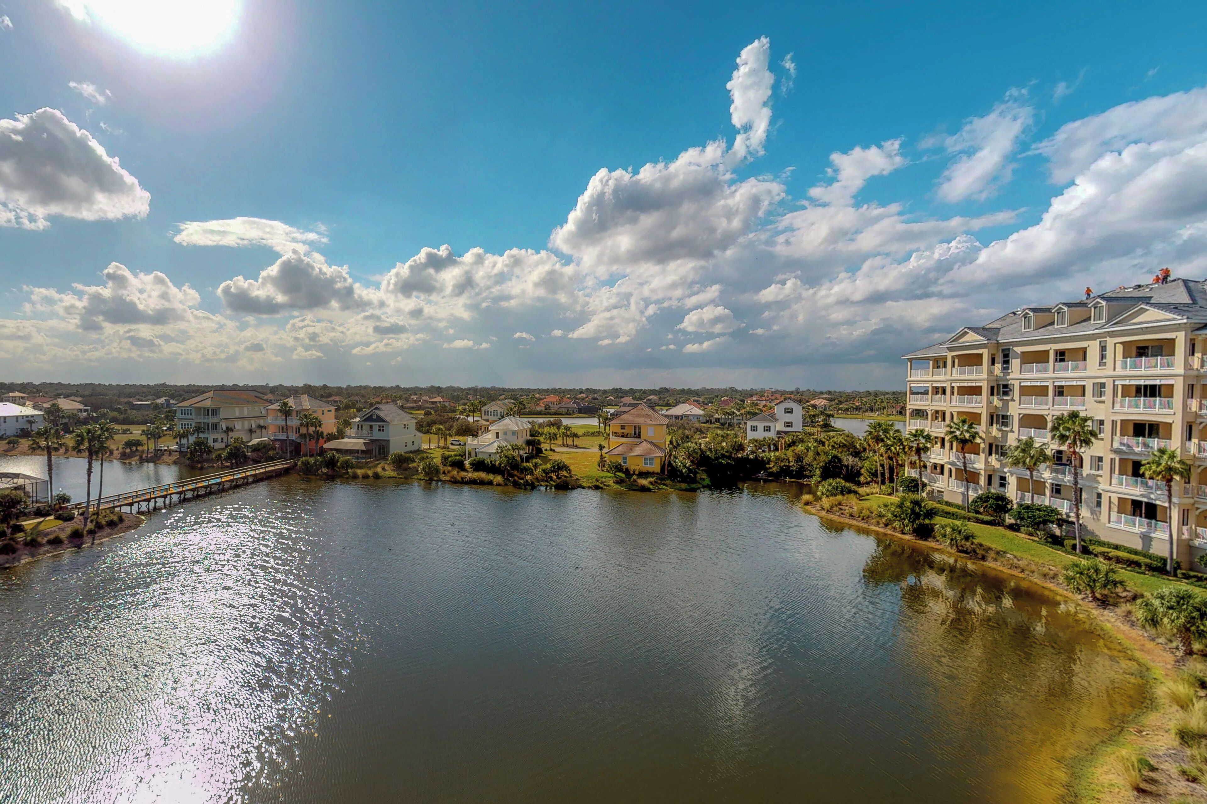 A waterfront hotel with multiple balconies, a bridge, and a lake.