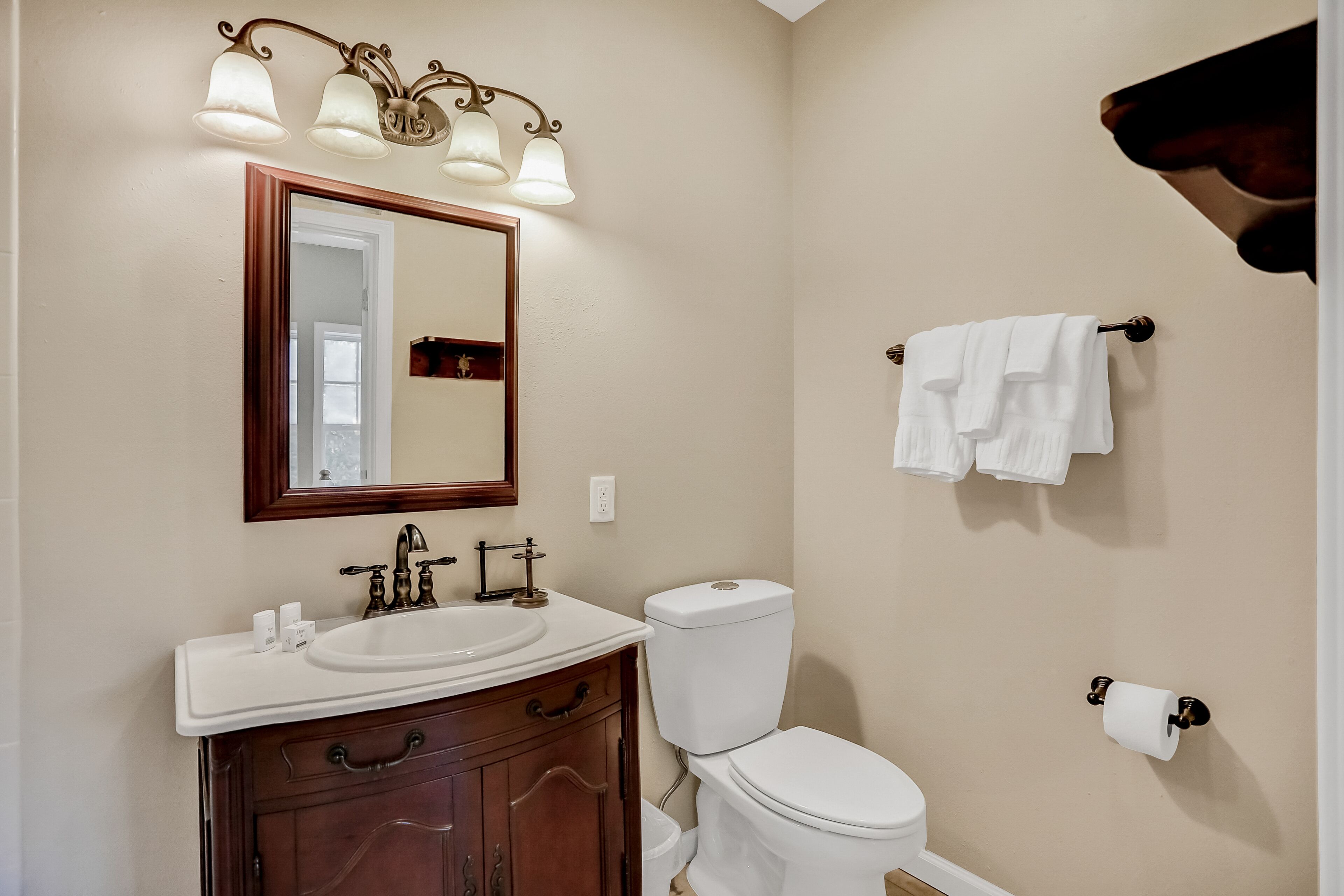 Une salle de bain équipée d’un lavabo, d’un miroir, de toilettes et d’un porte-serviettes.