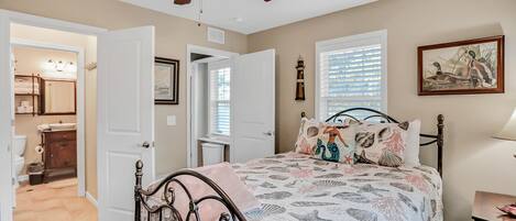A bedroom with a bed, a ceiling fan, a nightstand, and a painting on the wall.