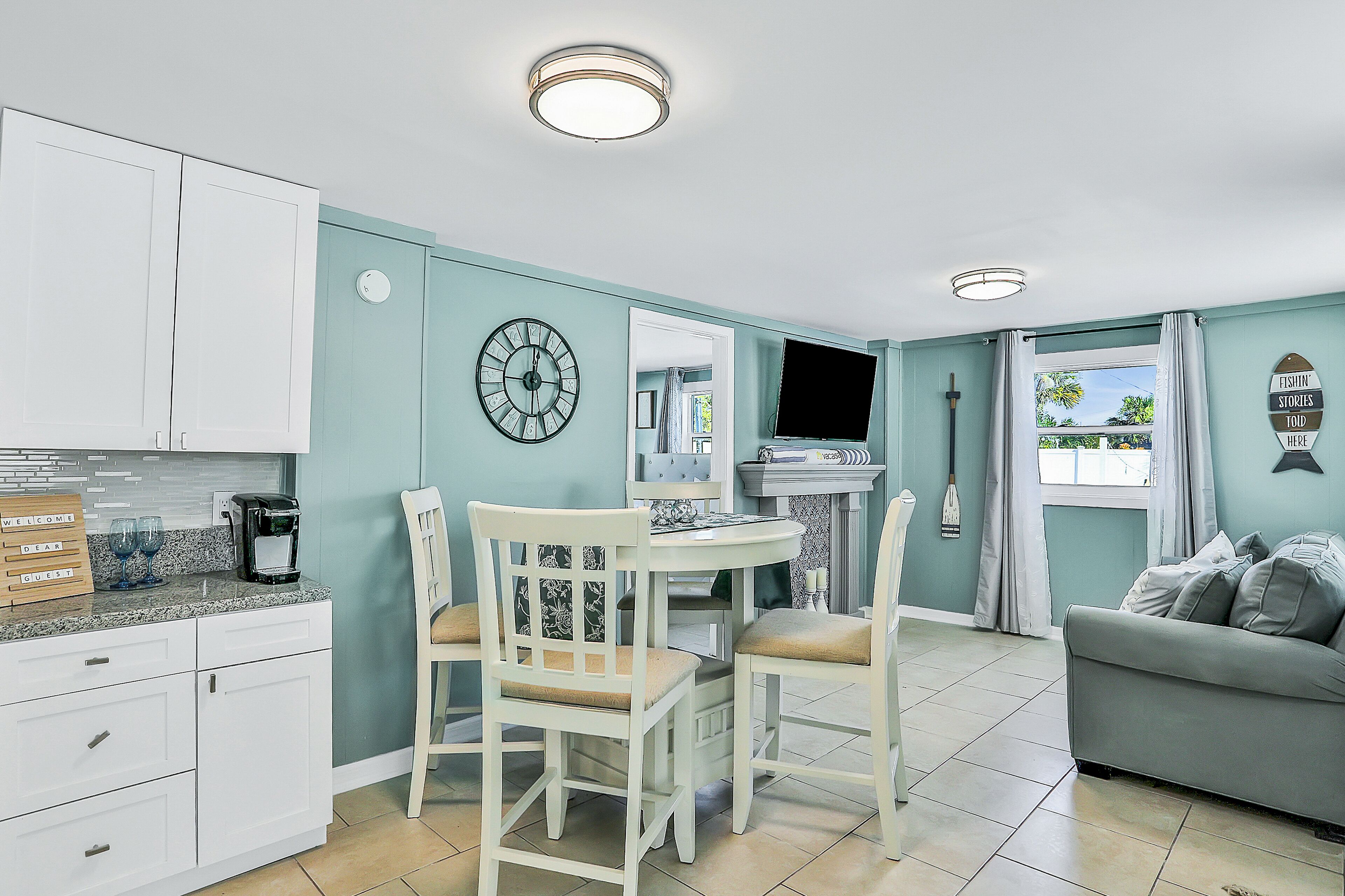 A modern kitchen with white cabinets, a coffee machine, and a dining area with a table and chairs.
