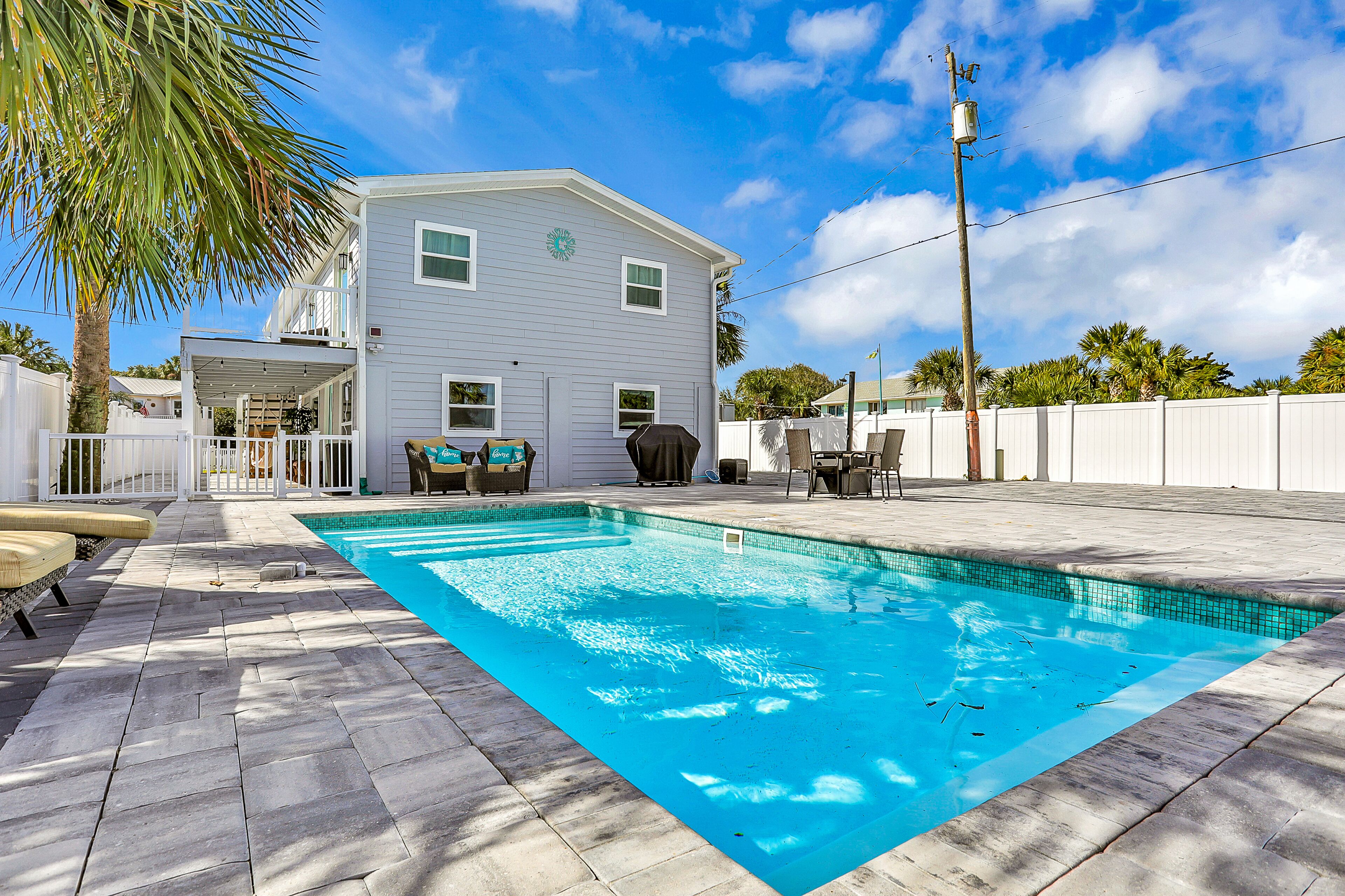 A swimming pool with a white house in the background.